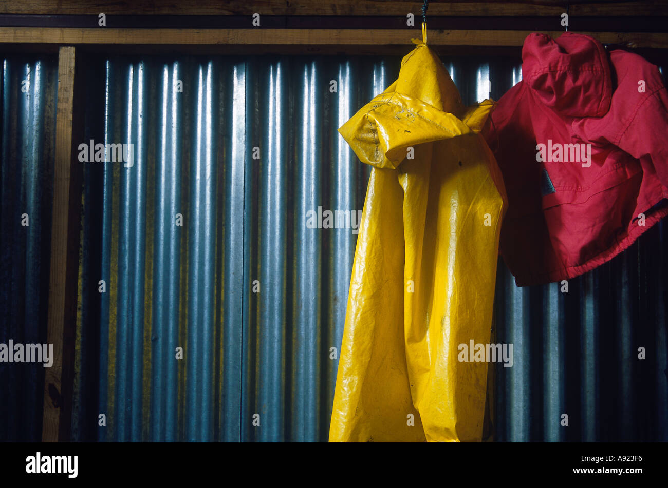 Wellblech Shack Regenjacke gelb mit roten Mantel aufhängen Stockfoto