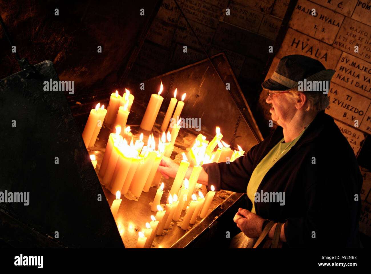Ältere Frau Anzünden von Kerzen in einem katholischen Schrein, Zagreb Kroatien. Stockfoto