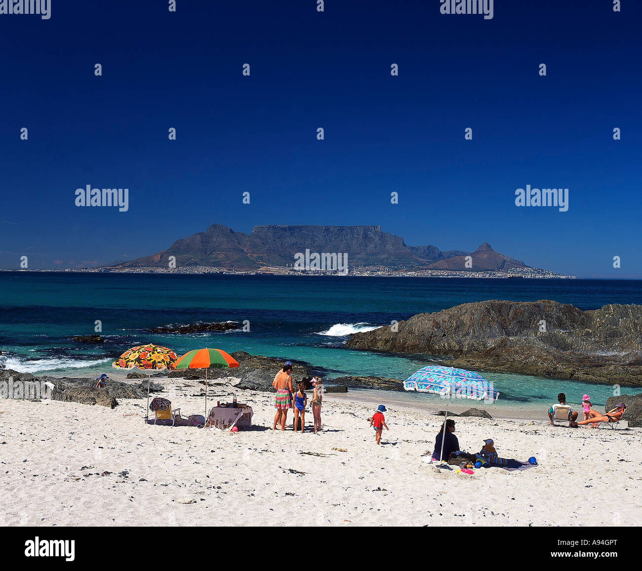 Badegäste entspannen am Blouberg Strand mit Tafelberg in der Bucht unter klaren sonnigen Himmel Kapstadt Stockfoto