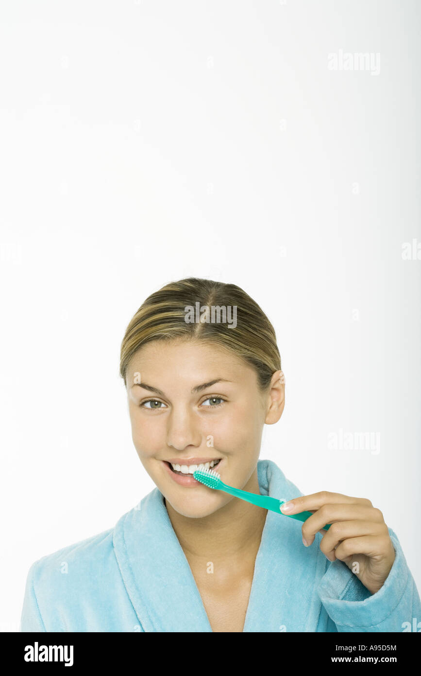 Junge Frau, die Zähne putzen, Blick in die Kamera Stockfoto