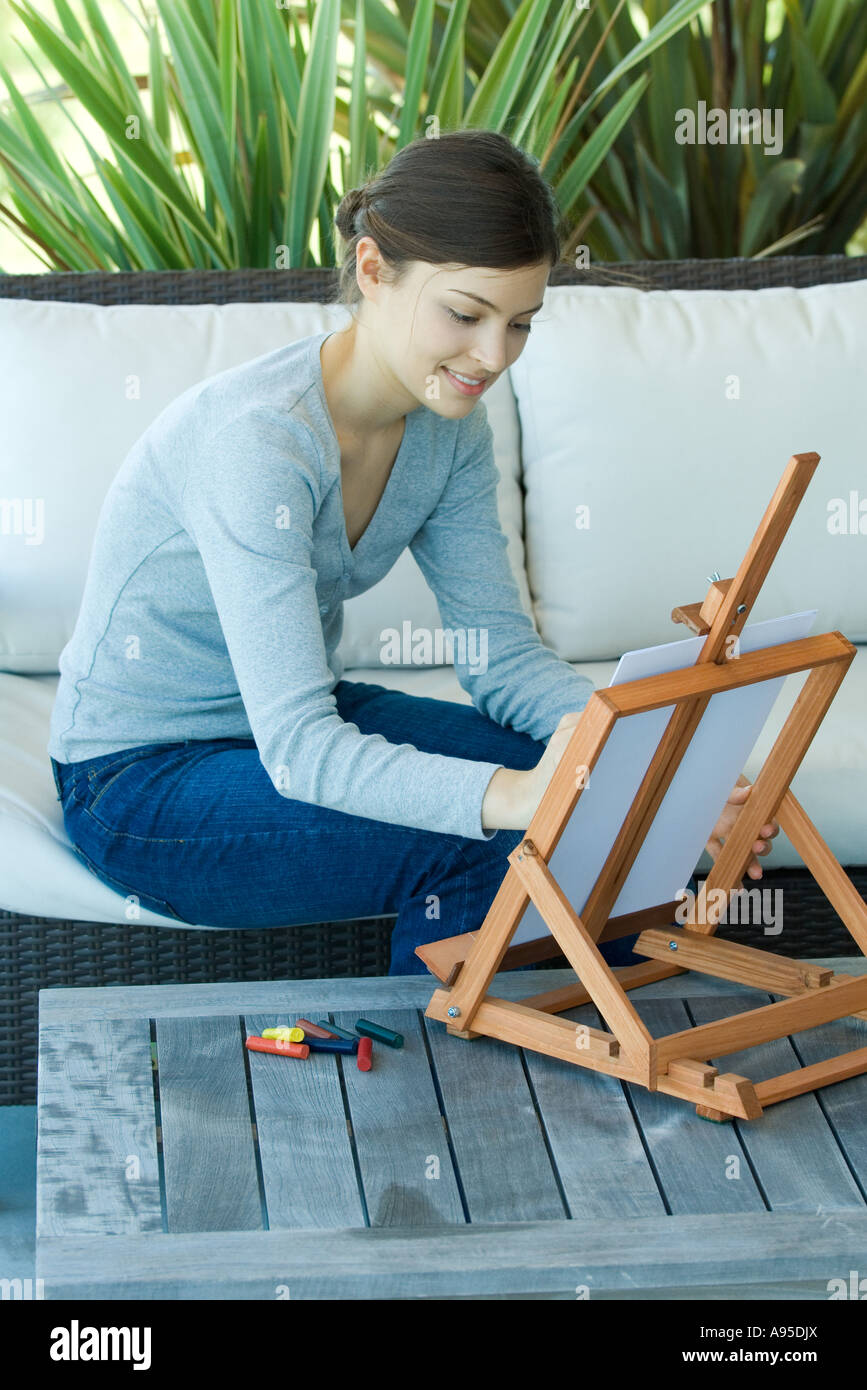 Junge Frau sitzt mit Staffelei, zeichnen mit Pastellkreiden Stockfoto