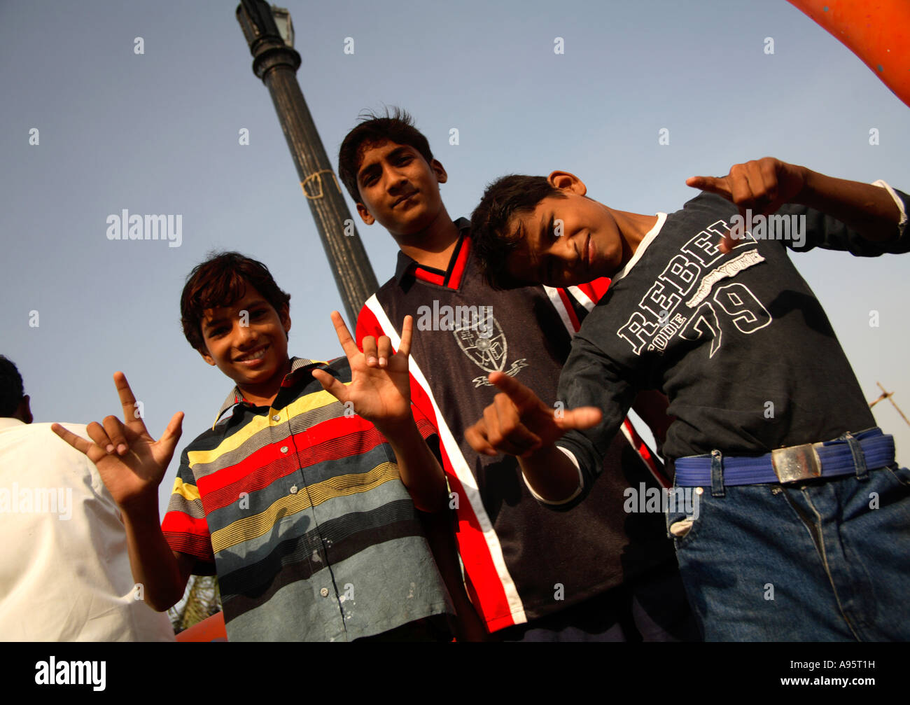 Junge indische Teenager geben 'I love you' Hand Signal/Gesten und zeigen auf Kamera in Gateway of India, Mumbai, Indien Stockfoto