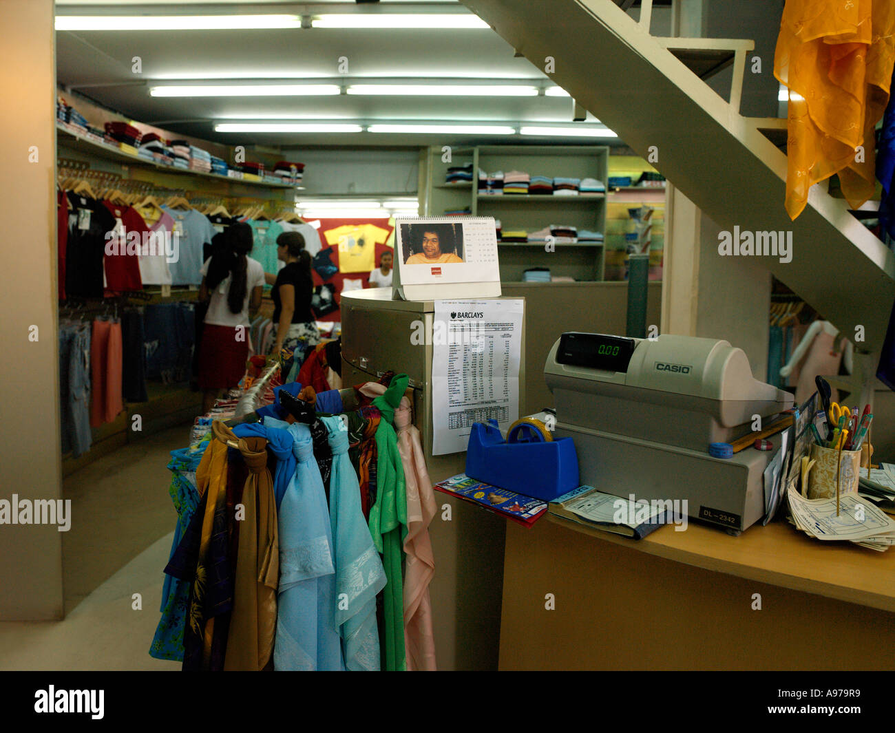 Port Louis Mauritius Mädchen und Verkäuferin T-Shirts im Billabong Shop mit Shri Baba Kalender religiöse Bild auswählen Stockfoto