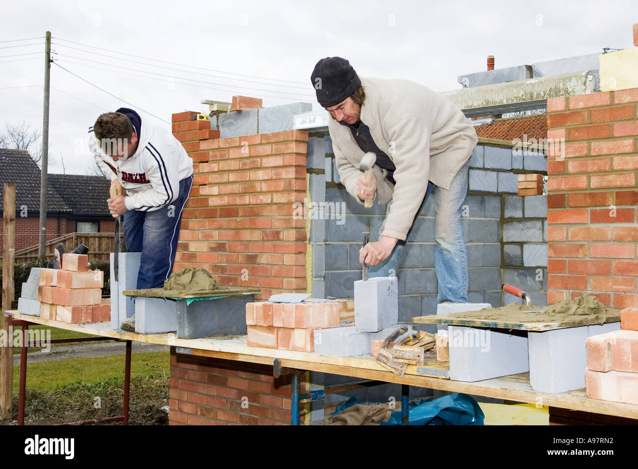 Maurer mit Stemmeisen Kropf und eine Säge um ^ schneiden Bausteine Stockfoto