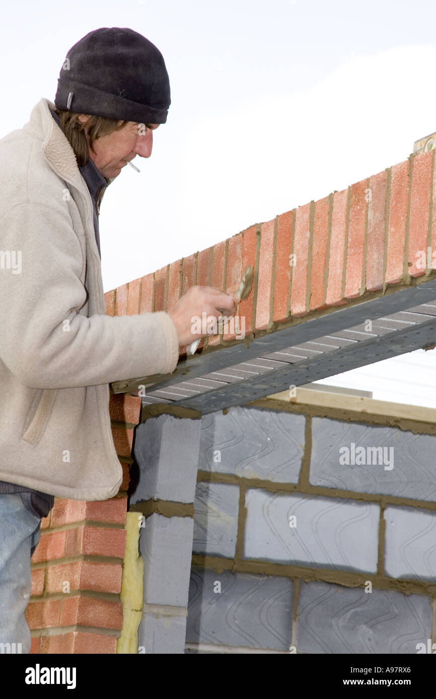 Maurer Bau einer Mauer und Glättung des Mörtels zwischen den Steinen Stockfoto