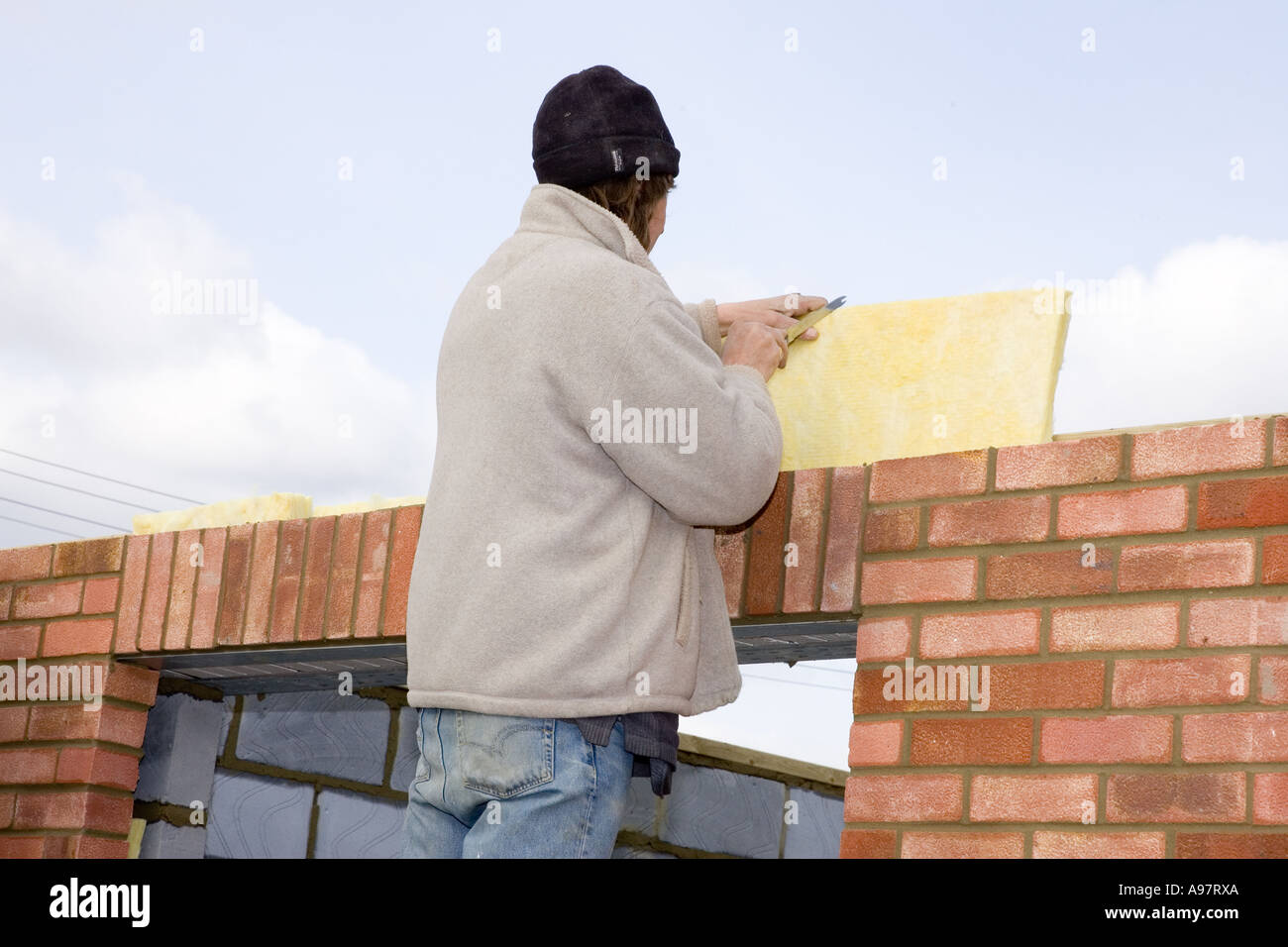 Einfügen von Glaswolle Dämmung Blätter in den Hohlraum der Wand Maurer Stockfoto