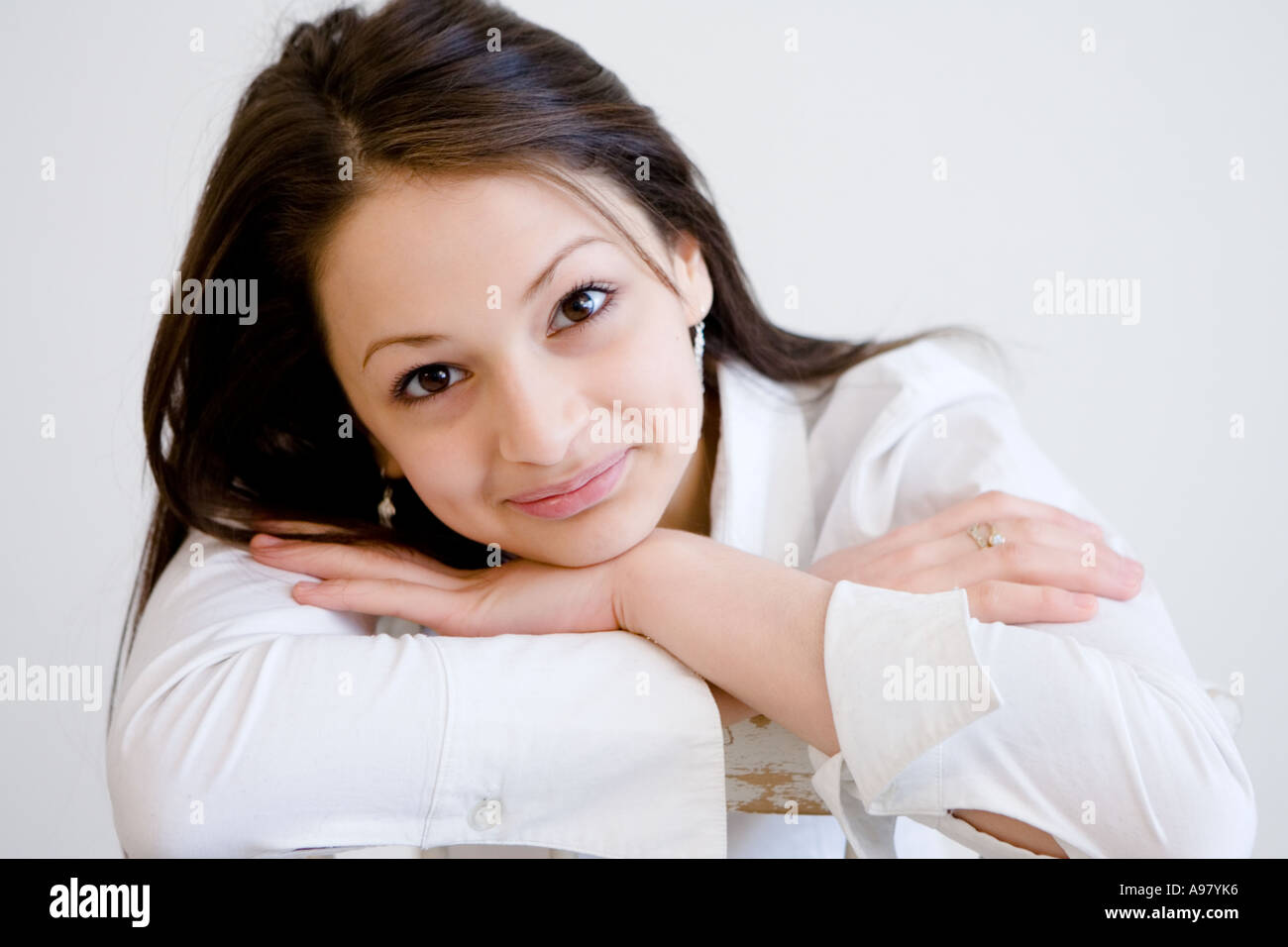 Junges hübsches Mädchen stützt ihren Kopf auf ihre Arme und lächelt mit Grübchen Stockfoto