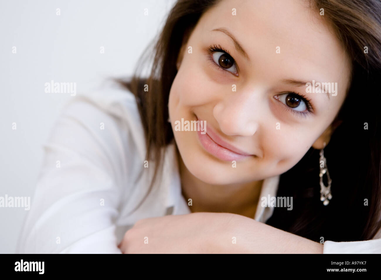 Junges hübsches Mädchen stützt ihren Kopf auf ihre Arme und lächelt mit Grübchen Stockfoto