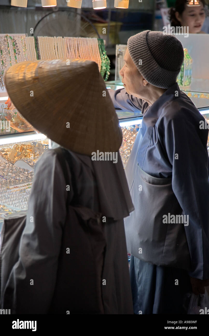 Nonne in konischen Hut und eine alte Frau in Strumpf Hut Einkaufen in Ho-Chi-Minh-Stadt (Saigon), Vietnam Stockfoto