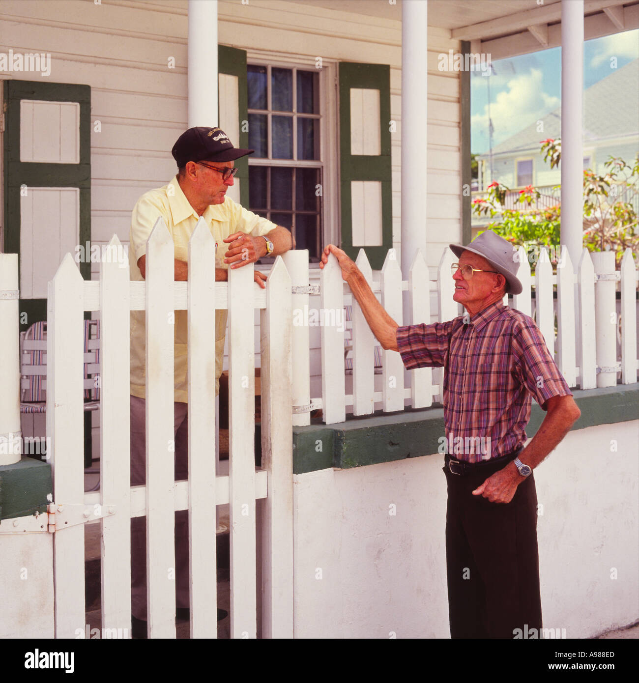 Lokalen älterer Mann im Gespräch mit einer anderen Insel-Bewohner über seinen weißen Gartenzaun bei Green Turtle Cay Abaco Insel der Bahamas Stockfoto