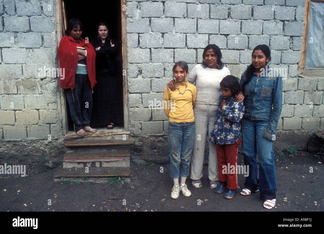 Eine Mutter und drei Kinder Pose vor einem Haus während zwei andere von Tür in Zigeuner Dorf Soard, Transylvania zu suchen. Stockfoto