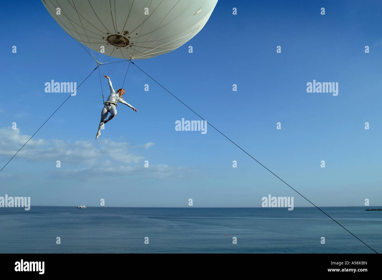 Eine riesige Helium-Ballon mit einer Antenne Trapezkünstler unter driftete über Zuschauer auf Dorset s Jurassic Coast Arts ausgesetzt Stockfoto