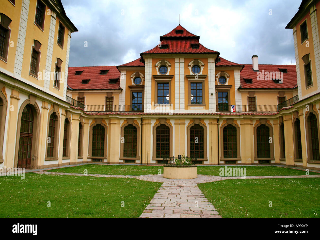 Zbraslavský zámek, ein historisches Schloss mit Bogenfenstern, roten Ziegeldächern und einem zentralen Innenhof, der von üppigem Grün umgeben ist. Stockfoto