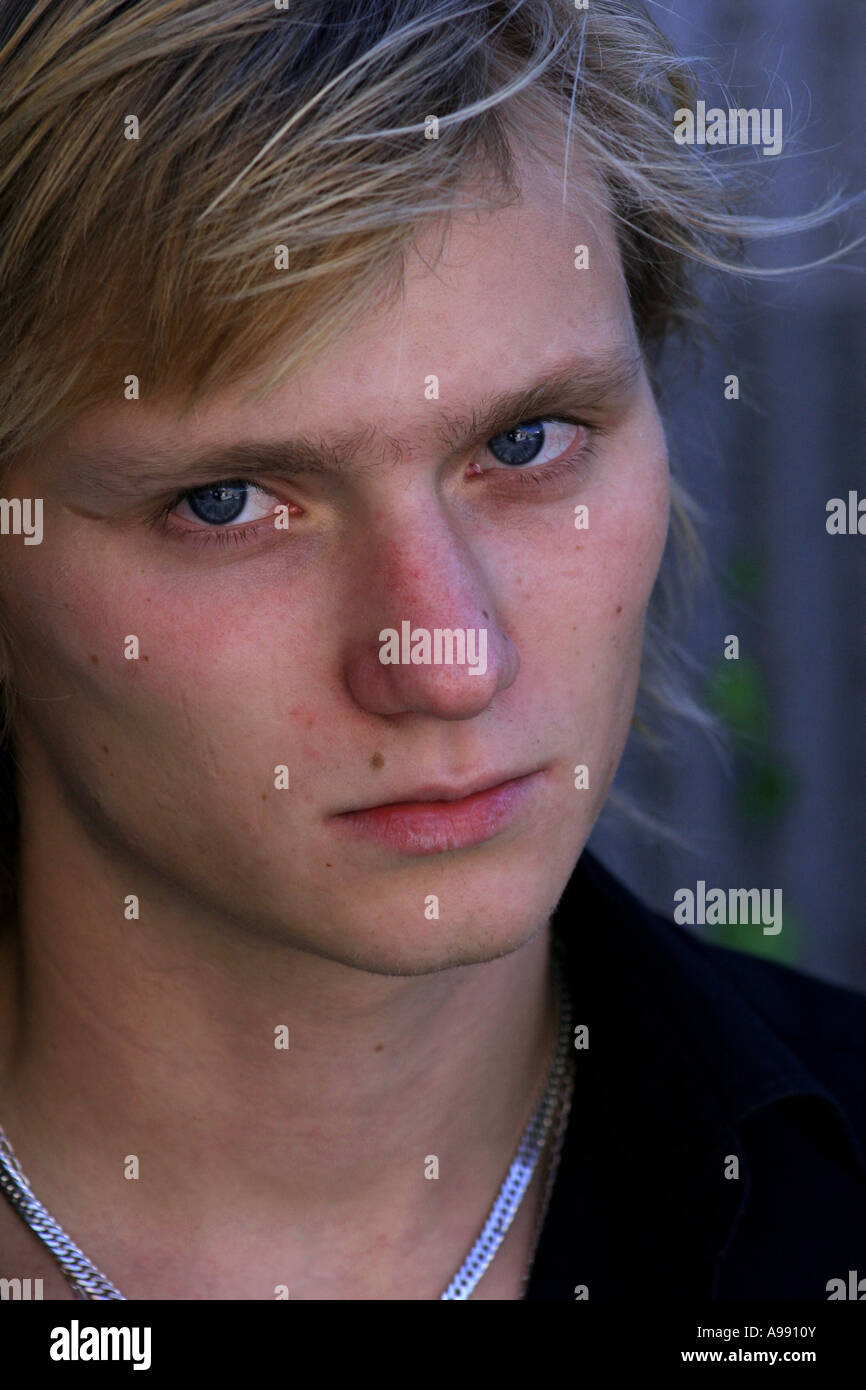 Nahaufnahme eines jungen Mannes mit blonden Haaren und durchdringenden blauen Augen, mit einem ruhigen, aber nachdenklichen Ausdruck in weichem natürlichem Licht. Stockfoto