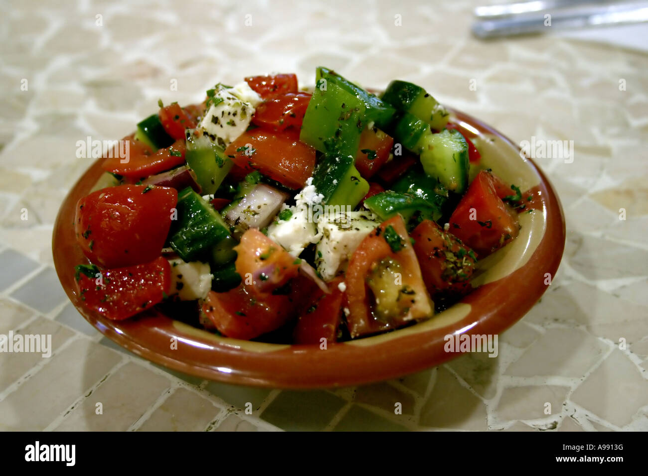 Einen frischen Libanesischen Salat mit Tomaten, Gurken, grüner Paprika, Zwiebeln und Fetakäse, in einer Schüssel serviert, mit Kräutern und Olivenöl abgeschmeckt. Stockfoto