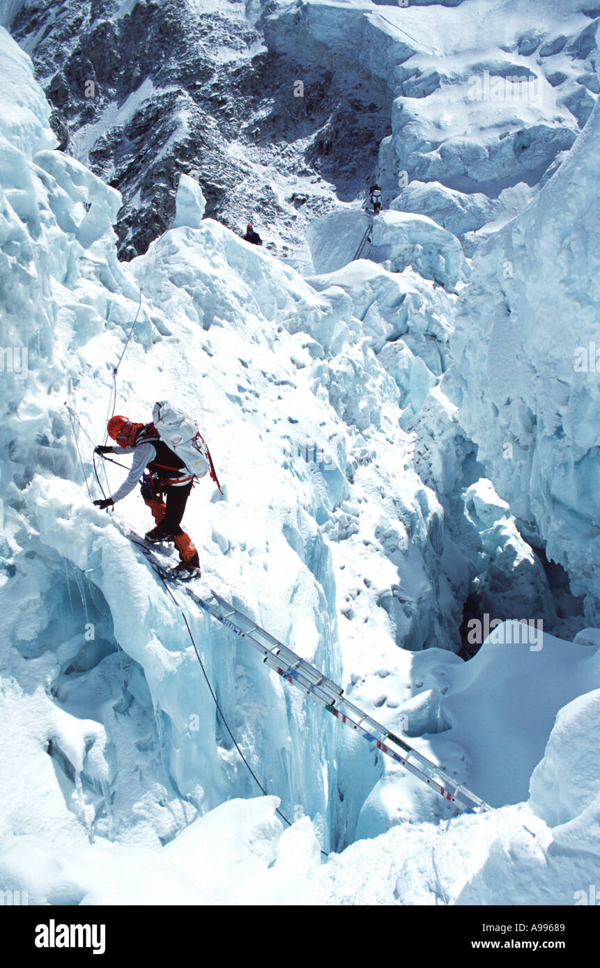 Bergsteiger verwendet einer Leiter zum Überqueren einer Schlucht in der Region Khumbu-Eisbruch auf Mt Everest zwei andere Kletterer vor ihm Stockfoto