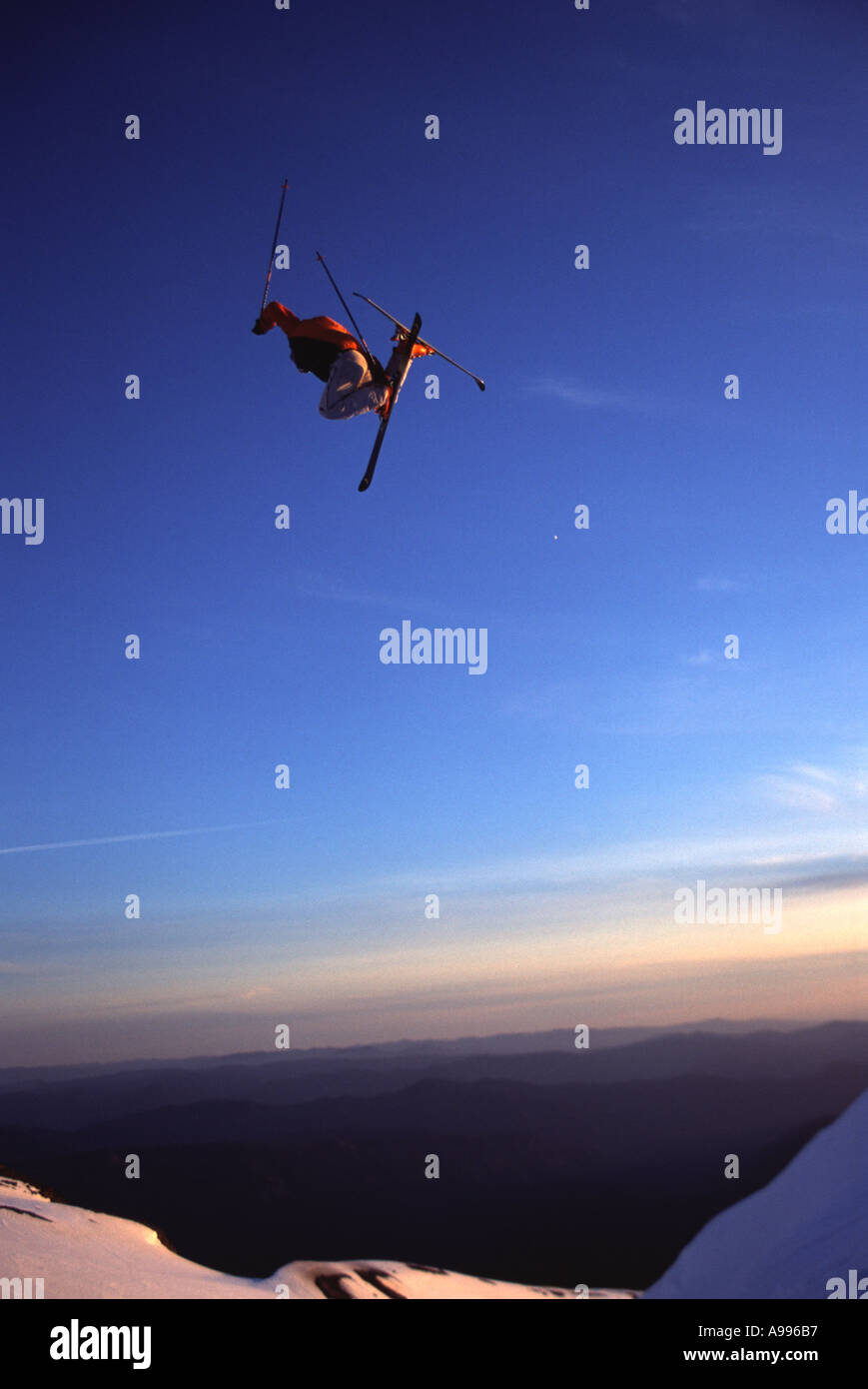 Skifahrer, die hoch in die Luft, als er von einem Felsvorsprung auf brillant klarem Wetter Mt Hood oder springt Stockfoto