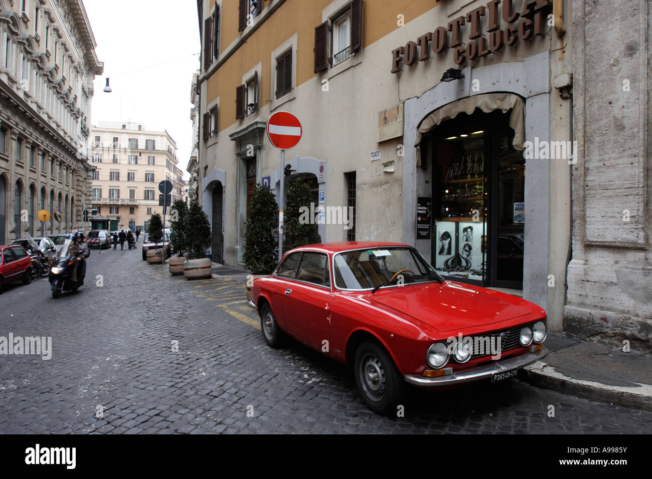 Ein rotes Auto Alfa Romeo Bertone parkt vor Foto-Shop Fotottica Colucci in Rom, Italien Stockfoto