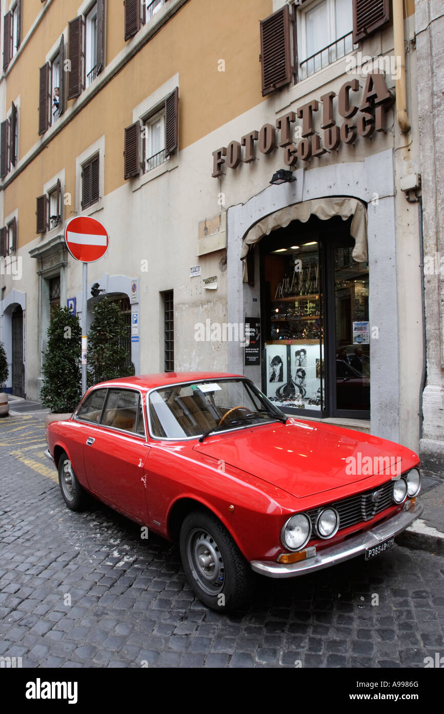 Ein rotes Auto Alfa Romeo Bertone parkt vor Foto-Shop Fotottica Colucci in Rom, Italien Stockfoto