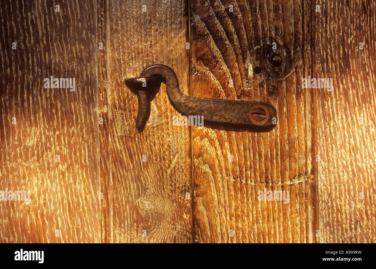 Nahaufnahme von kleinen alten getrübt Metallhaken oder Verschluss hakte in angrenzenden Schleife getragen gemaserte Holz Tür geschlossen zu halten Stockfoto