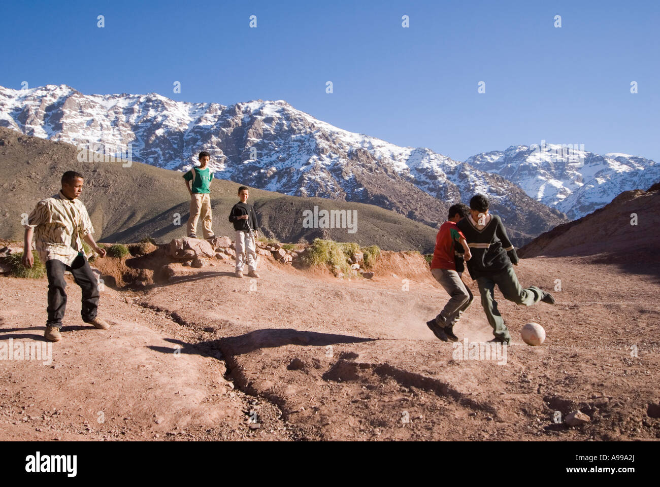 Kinder spielen Fußball auf einem Berg über ihr Dorf im hohen Atlas-Gebirge in Marokko Stockfoto
