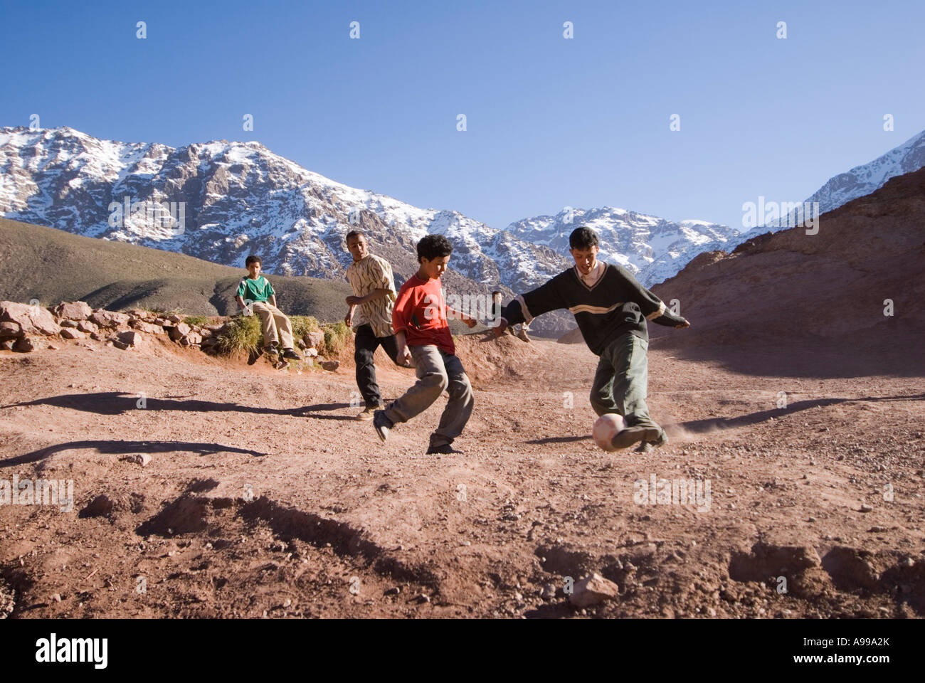 Kinder spielen Fußball auf einem Berg über ihr Dorf im hohen Atlas-Gebirge in Marokko Stockfoto