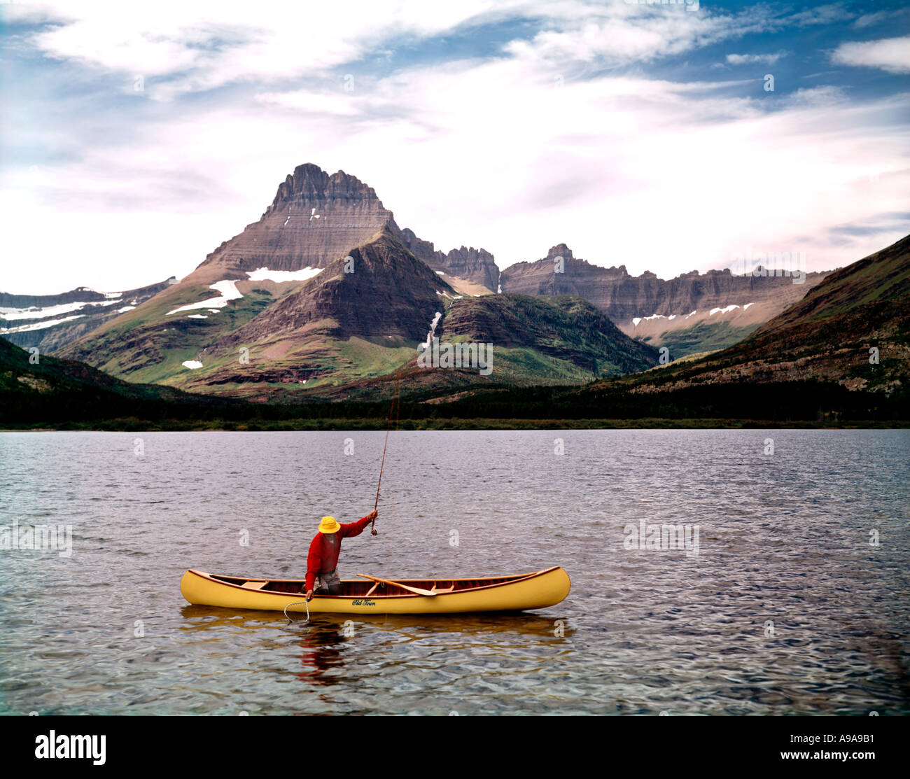 Glacier-Nationalpark in Montana zeigt Fischer im Kanu am Swiftcurrent Lake mit Mount Wilbur und Ptarmigan Wand Stockfoto