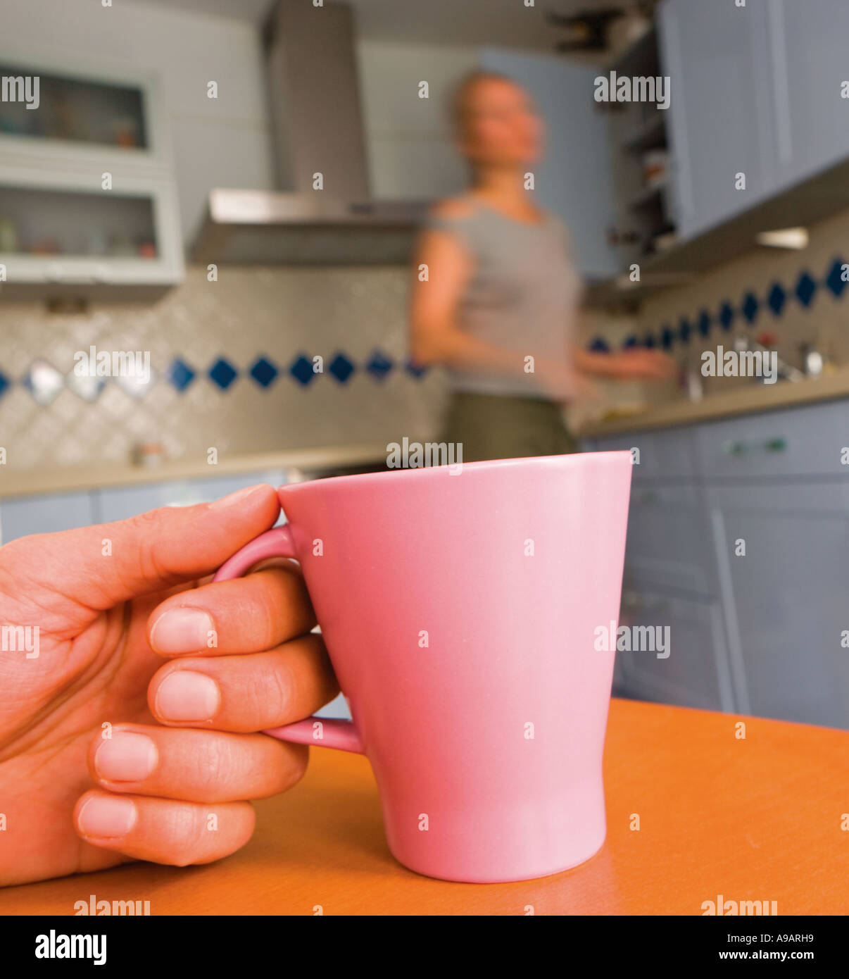 Junge Frau in der Küche, im Gespräch mit unsichtbaren Person halten Tasse Stockfoto