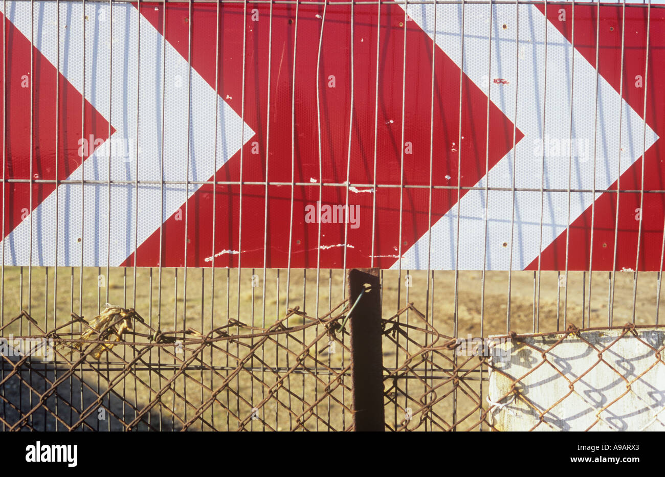 Rote und weiße Chevron Richtung Roadsign mit Draht Zäune und wasteground Stockfoto
