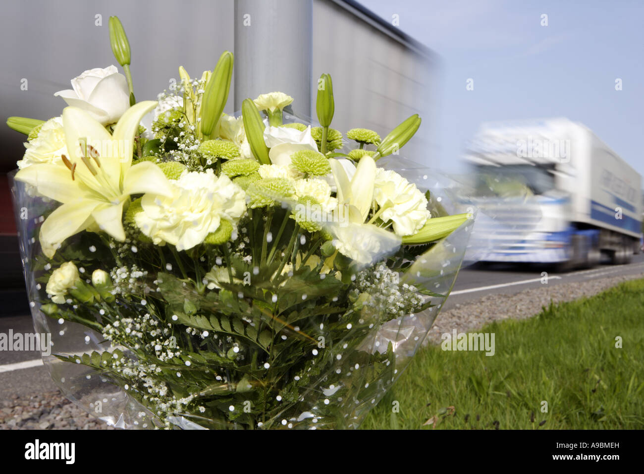 Tod auf den Straßen LKW Beschleunigung vorbei ein floral Tribute Kennzeichnung der Stelle einer tödlichen Straße Verkehrsunfall Stockfoto