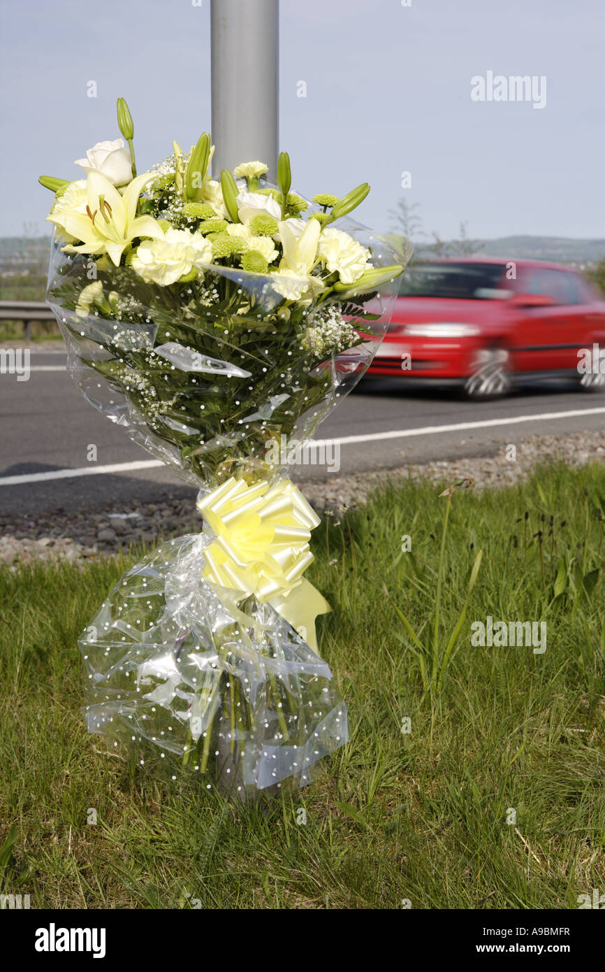 Tod-Auto beschleunigt vorbei ein floral Tribute Kennzeichnung der Stelle von einem tödlichen Verkehrsunfall Stockfoto