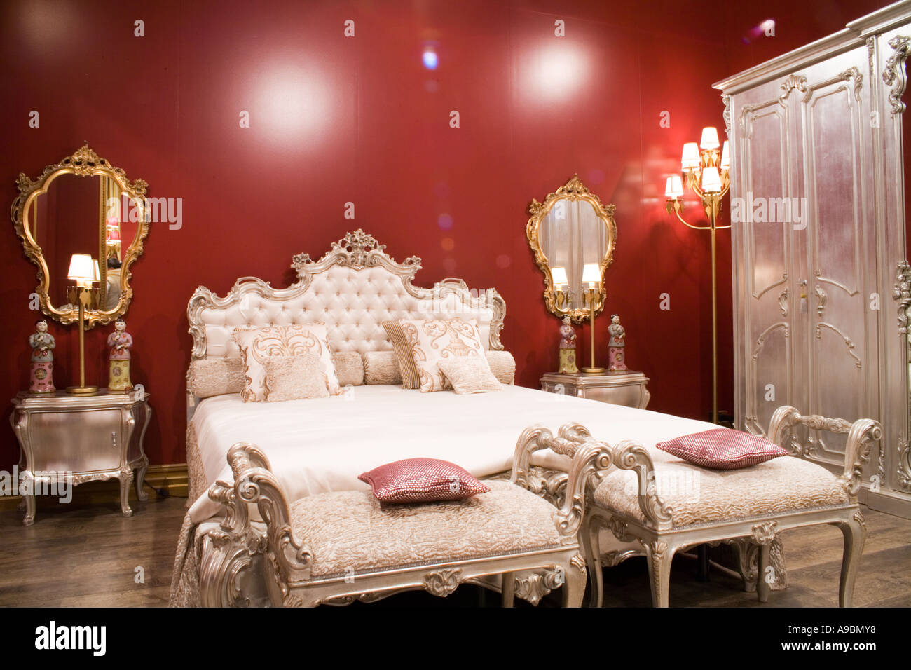 Silber fertigen Capitonè Bett mit Dormeuses zu seinen Füßen und Kleiderschrank Schlafzimmer rote Wand Stockfoto