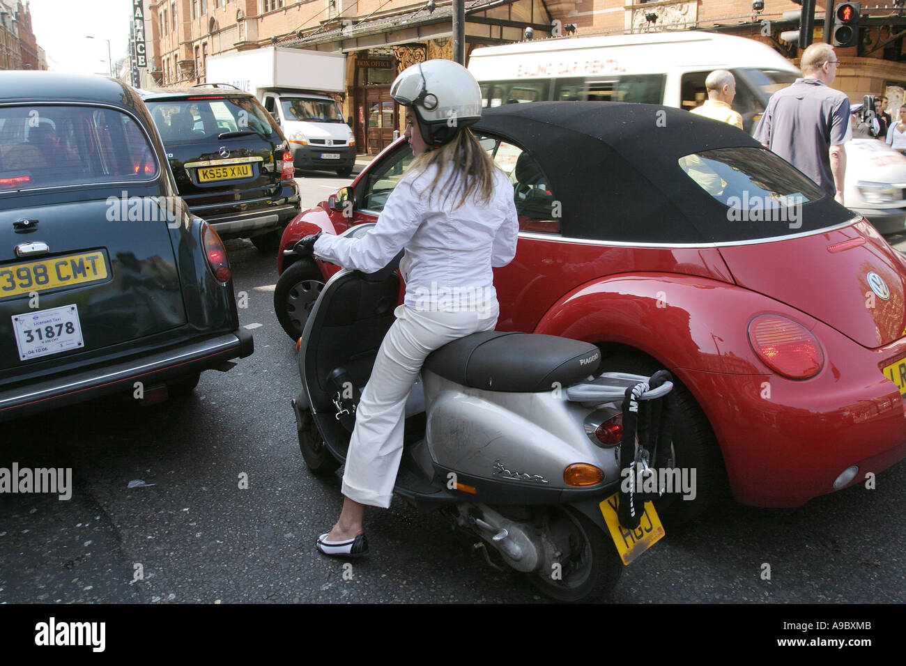 Ein weibliche Moped Fahrer wartet für den Verkehr zu bewegen, Shaftesbury Avenue, London, UK. 2006. Stockfoto