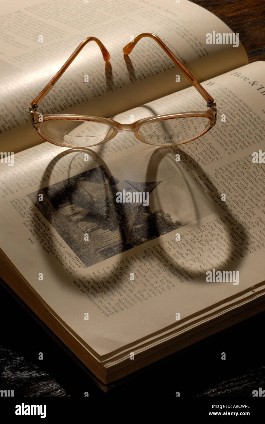 Ein paar Brillen sitzen an einem Buch und wirft einen langen Schatten Stockfoto