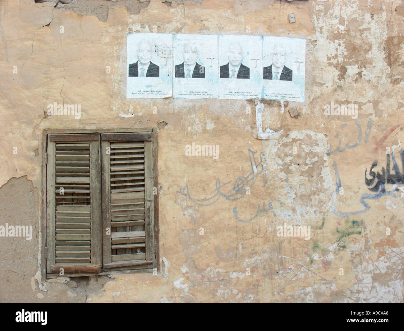 Alten Gebäude in El Bawiti weitgehend aus Lehmziegeln gebaut Staubschutzklappen Fenster mit politischen Plakaten Stockfoto