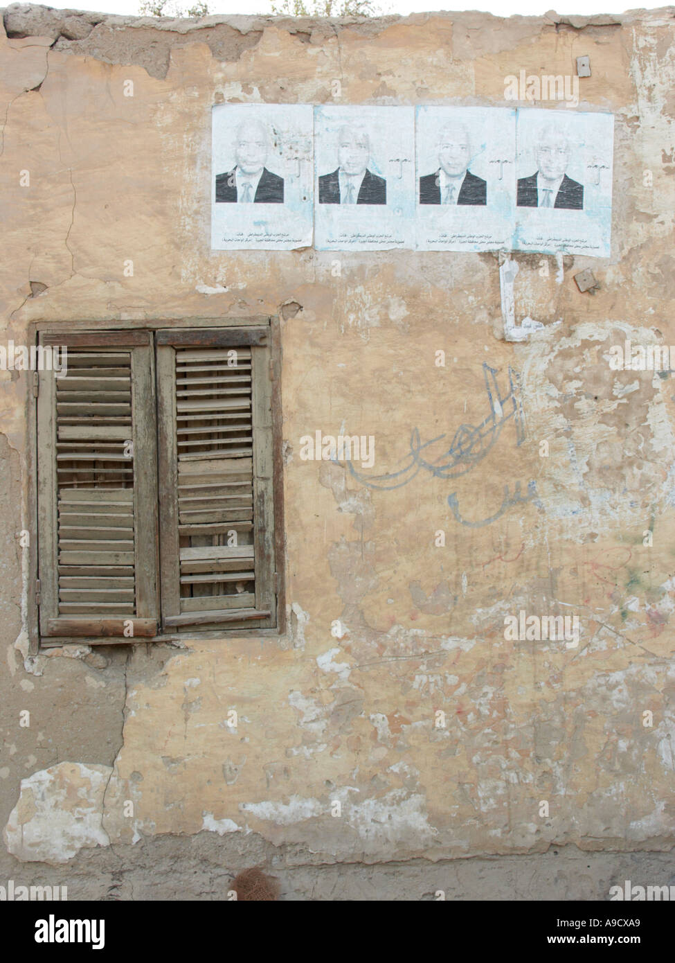 Alten Gebäude in El Bawiti weitgehend aus Lehmziegeln gebaut Staubschutzklappen Fenster mit politischen Plakaten Stockfoto