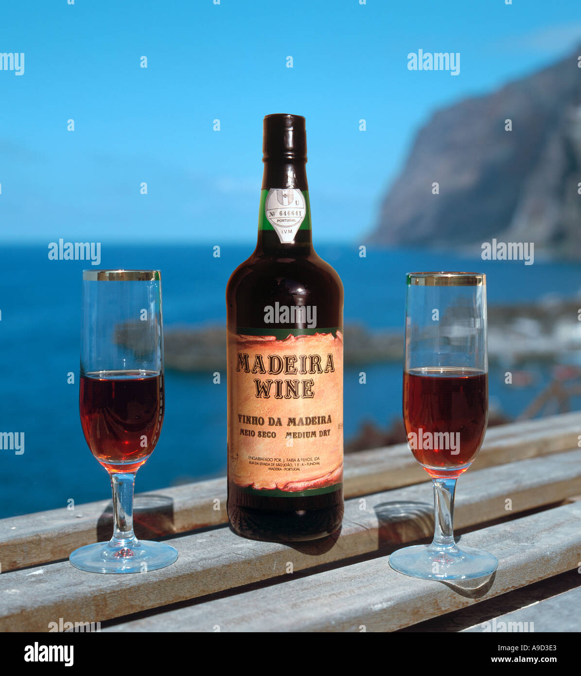 Eine Flasche Wein aus Madeira mit zwei Gläser mit den der Fischerei Dorf von Camara de Lobos hinter, Madeira, Portugal Stockfoto