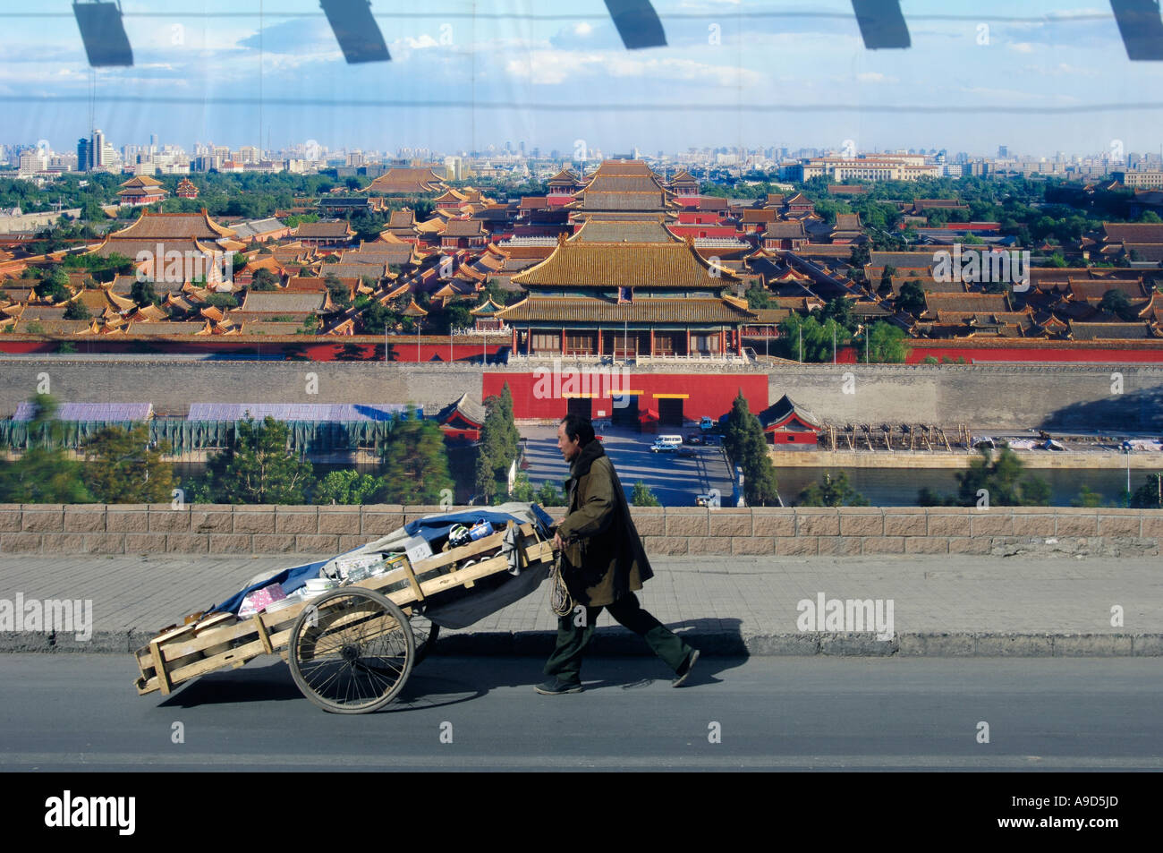 Ein chinesischer Mann drückt ein Flachbett vorbei an einem riesigen Plakat Featuing verbotene Stadt in Peking 2006 Stockfoto