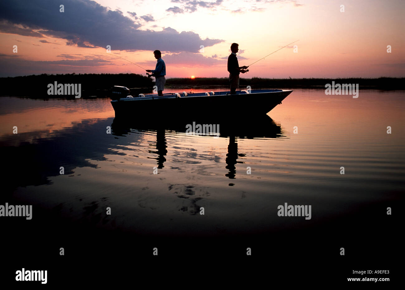 Zwei Fischer stehen in Aboat bei Sonnenaufgang Shakawe Okavango Delta, Botswana Stockfoto