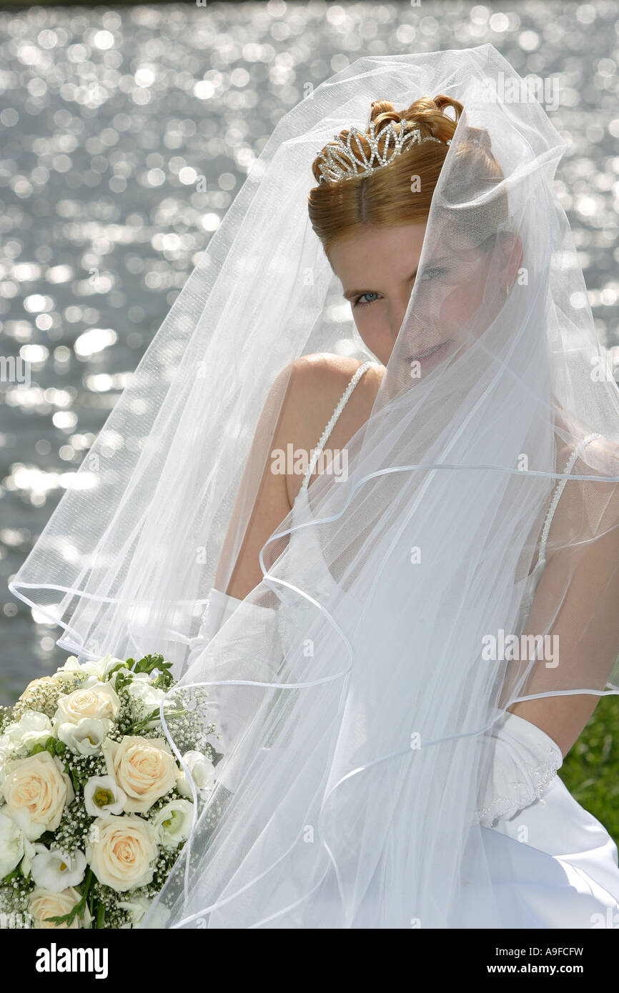Ein Porträt einer Braut an ihrem Hochzeitstag einen Blumenstrauß mit einem Schleier über ihr Gesicht zu halten Stockfoto