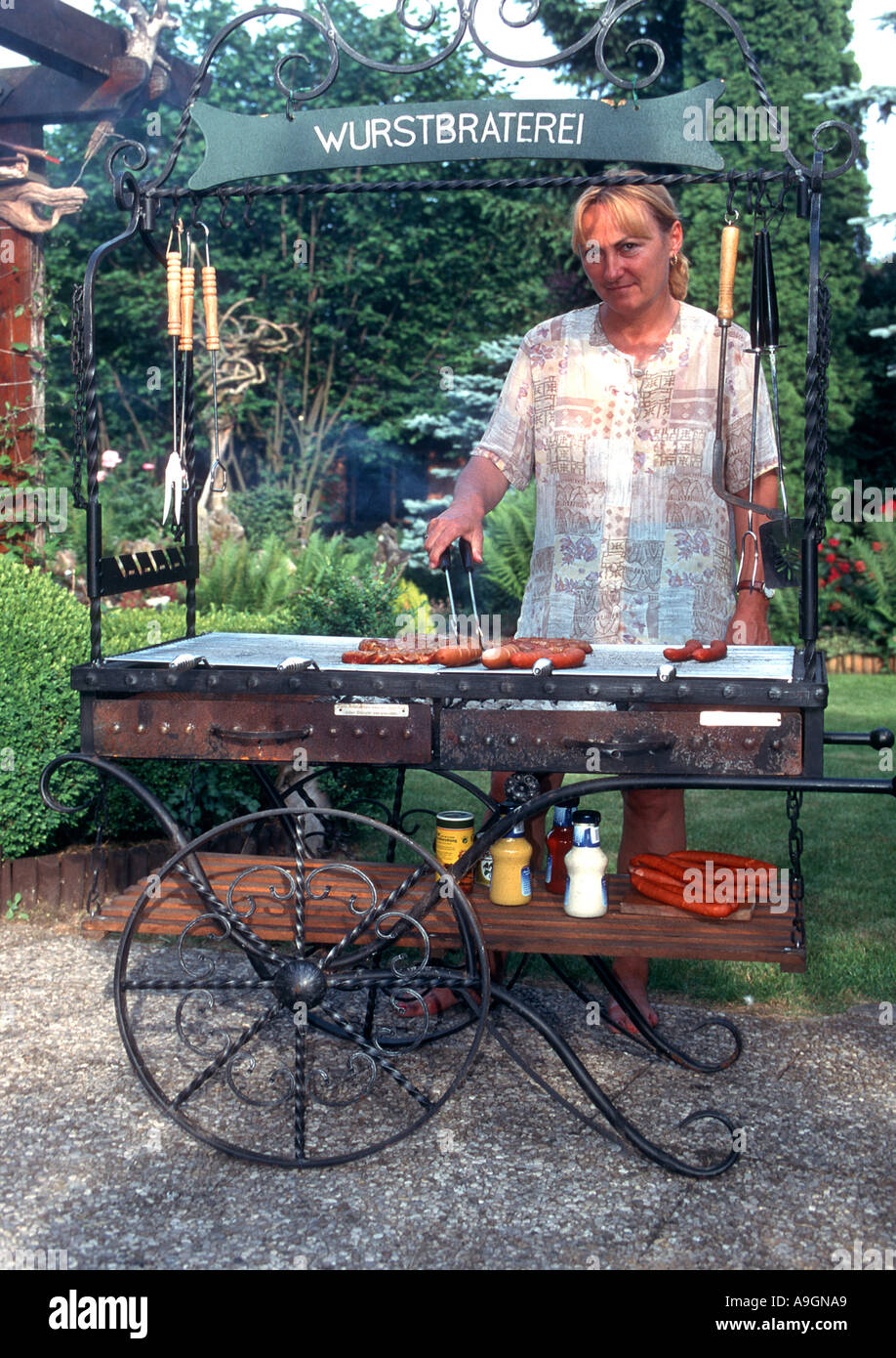 Frau Würstchen auf dem Grill im Garten Stockfoto