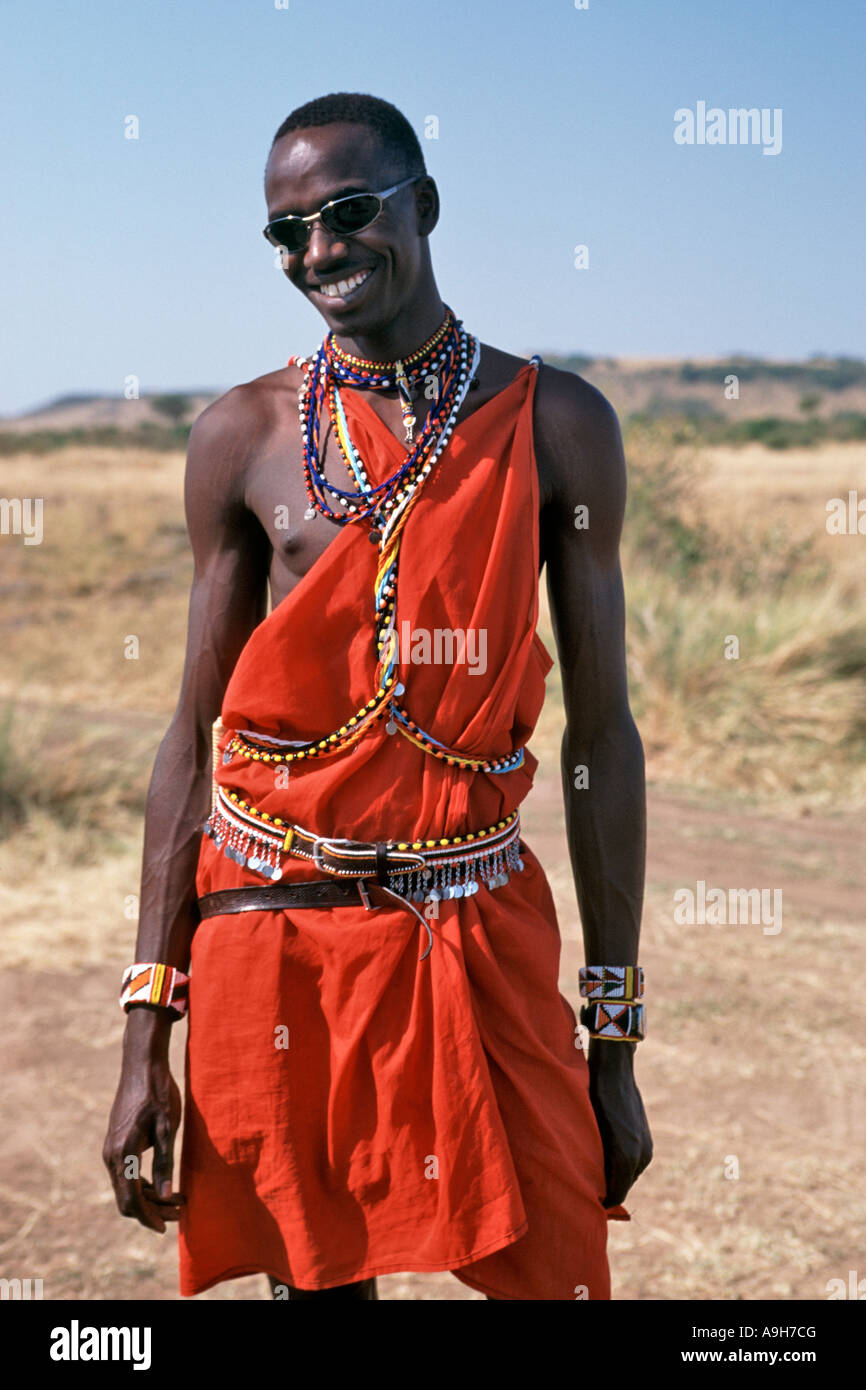 Ein Masai Mann in traditioneller Kleidung Posen mit Sonnenbrille in der Masai Mara in Kenia. Stockfoto