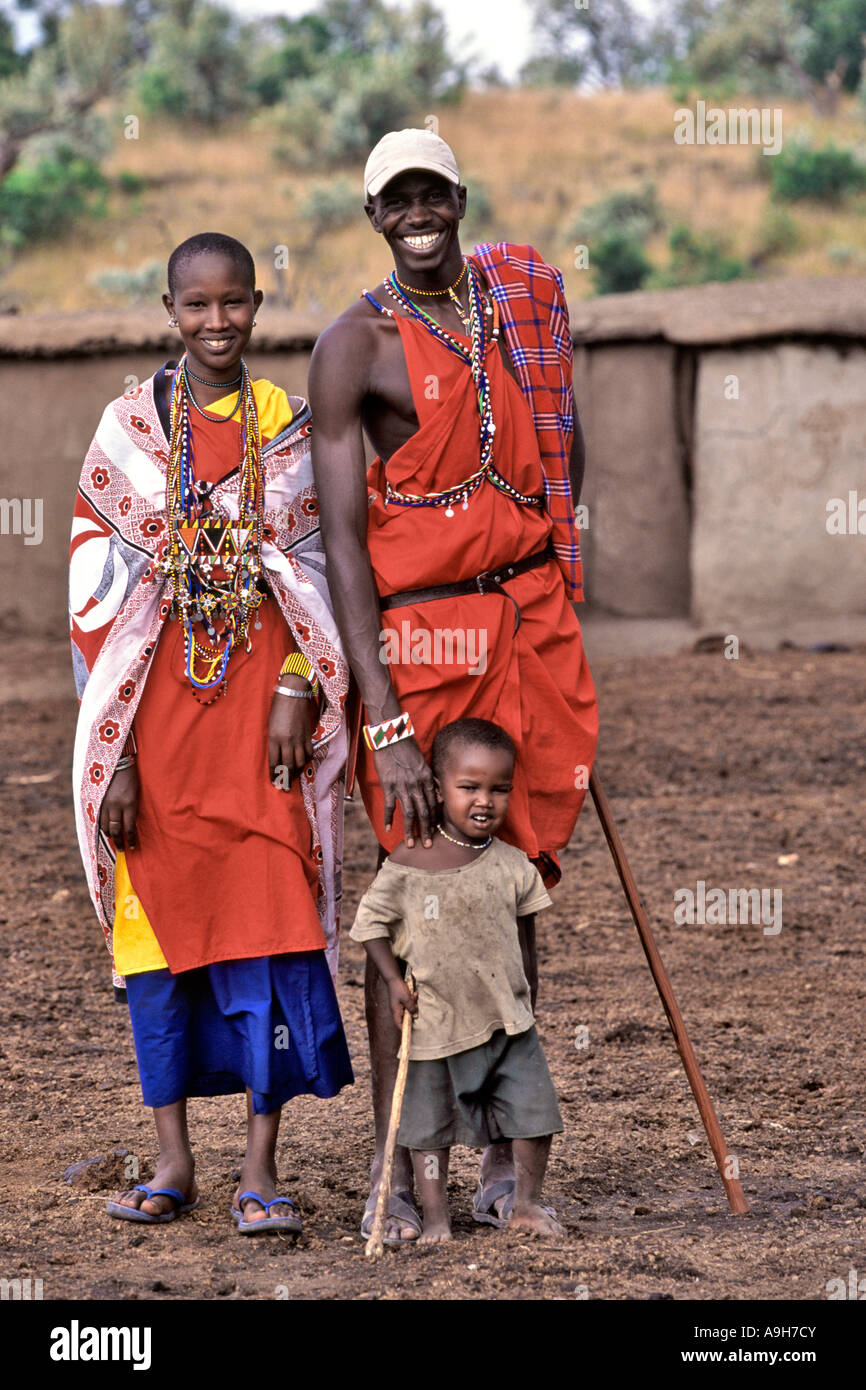 Ein paar Masai in traditionellen Outfits posieren mit ihrem Kind in ihrem Dorf (genannt ein Manyatta) in der Masai Mara in Kenia. Stockfoto