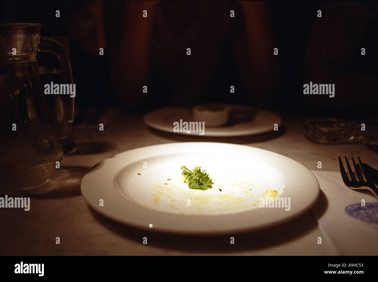 Leeren Teller im abgedunkelten Raum mit Figur stand im Schatten hinter Stockfoto