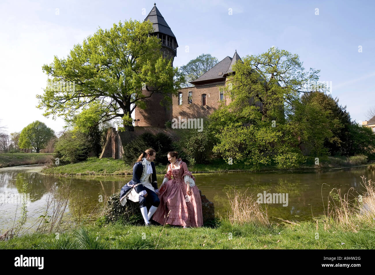 Junges Paar, gekleidet im Stil des Rokoko posiert vor der Wasserburg Linn, Krefeld, NRW, Deutschland Stockfoto