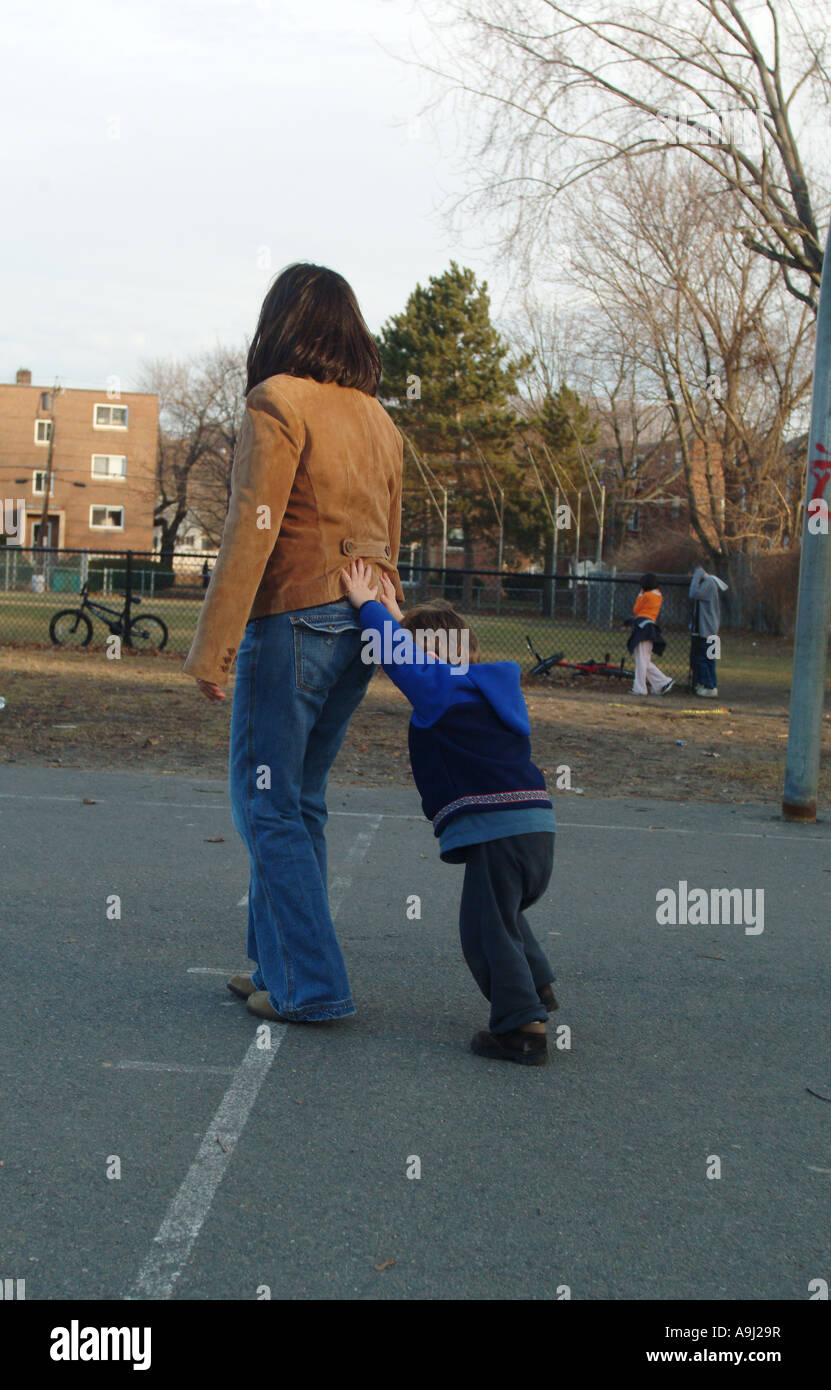 Drei-jährige (3) Kind am Spielplatz schiebt seine Mutter im Akt des Widerstands. Stockfoto