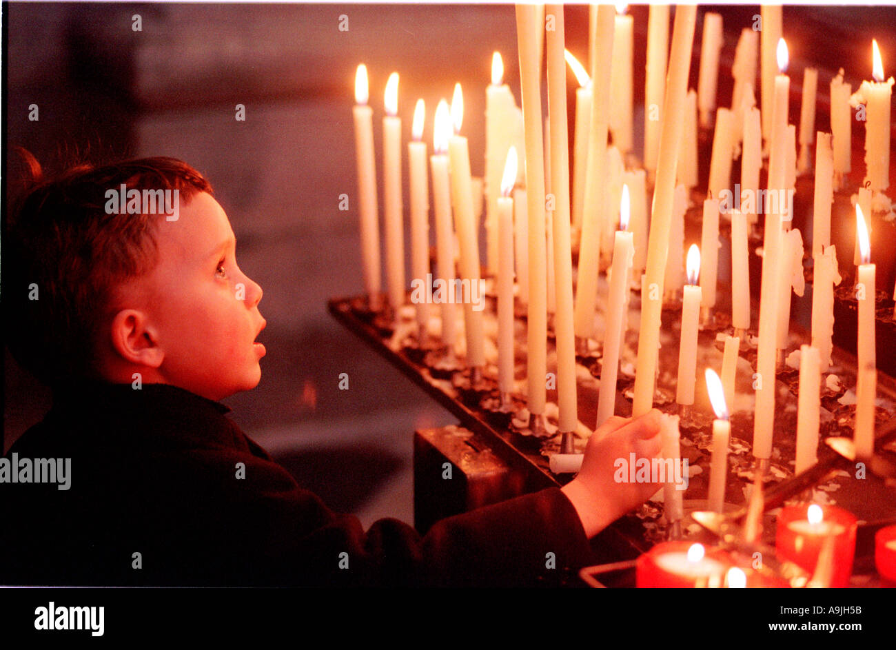 ein Junge in einer Kirche eine Kerze anzünden Stockfoto