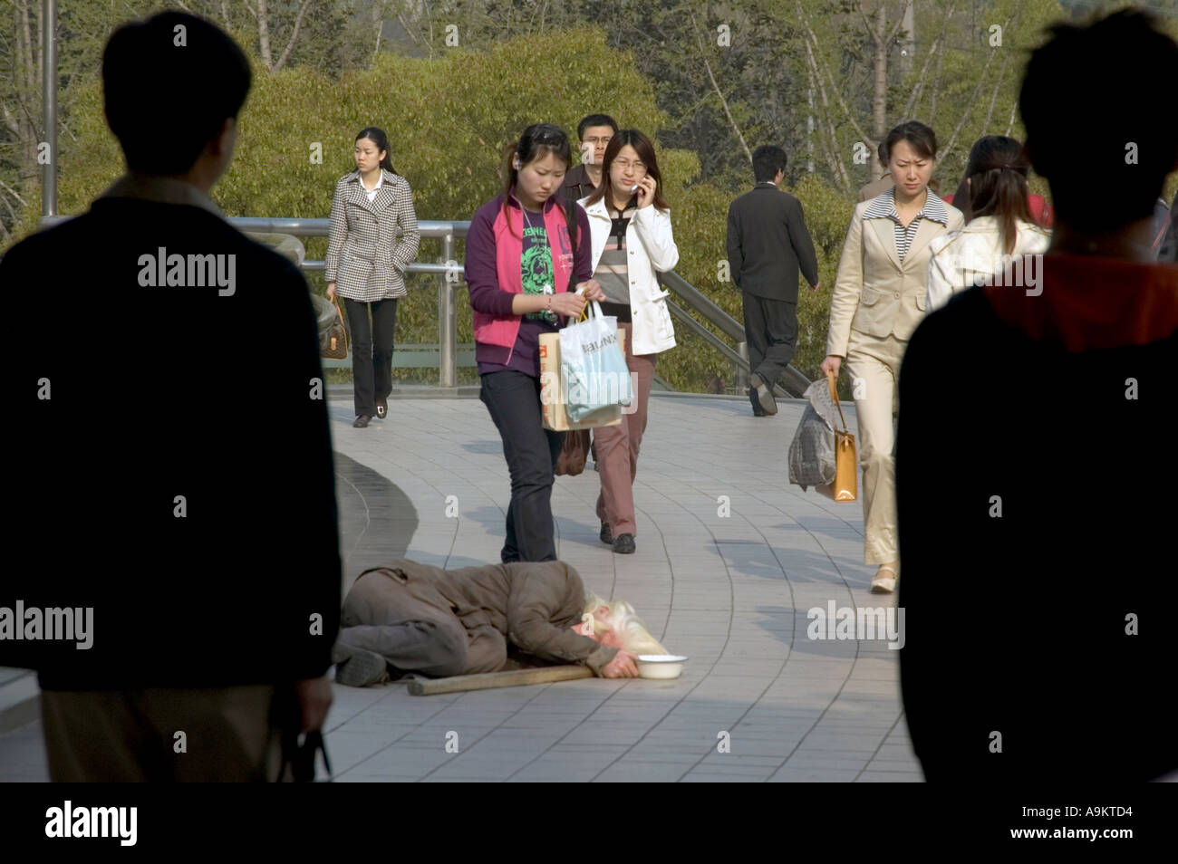 AM FRÜHEN MORGEN PENDLER VORBEI AN OBDACHLOSEN MENSCHEN S SQUARE SHANGHAI CHINA Stockfoto