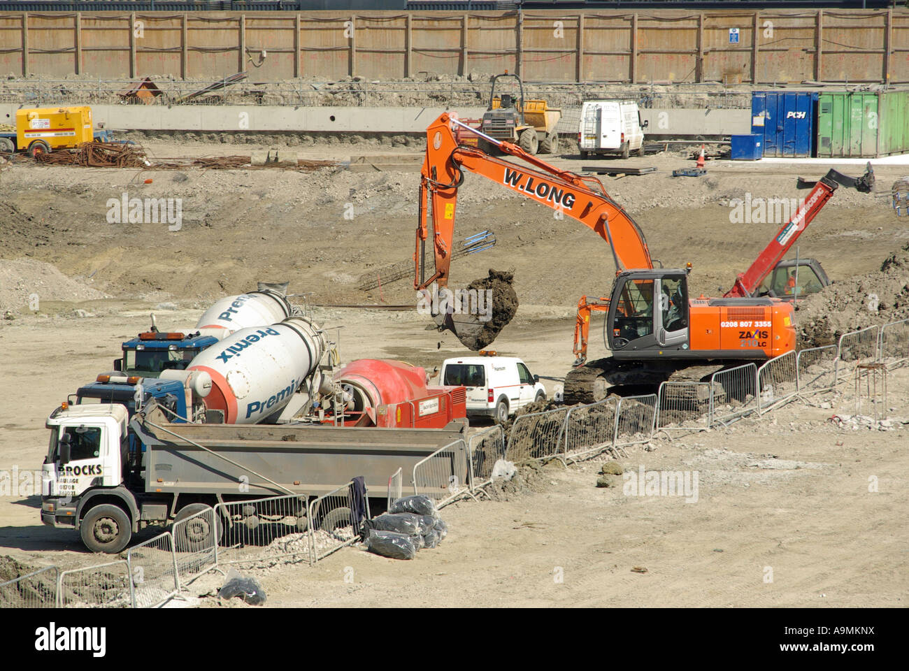 Bau Baustelle Beton Betonmischer Lkw und Bagger digger Maschine laden Erde aus Stiftungen Grundlagen in Lkw-East London Großbritannien Stockfoto