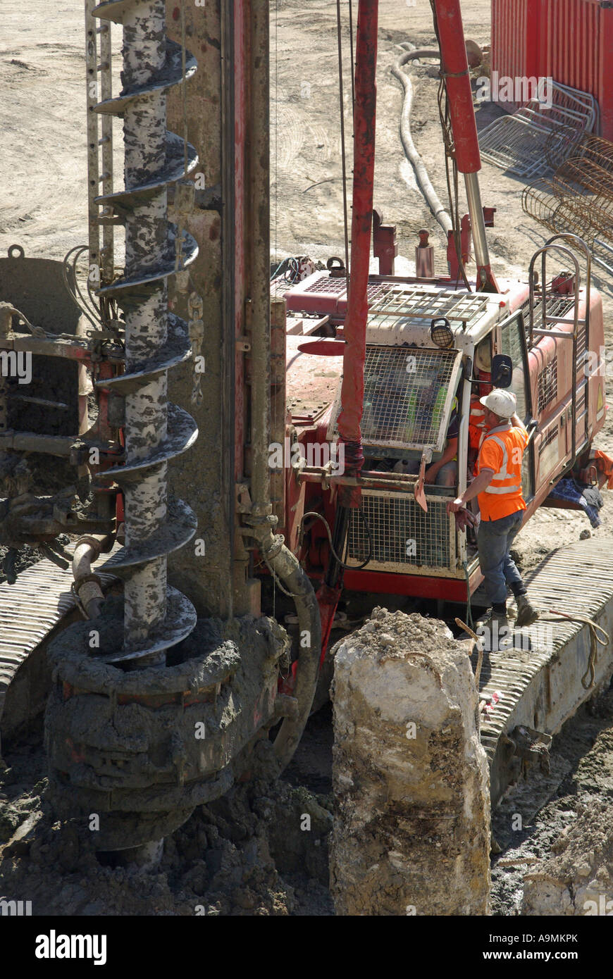 Grundlagen langweilig Schnecke auf große piling Rigs Maschine neben Betonpfahl & Arbeiter stehen auf Caterpillar Gleisbau Baustelle London UK Stockfoto